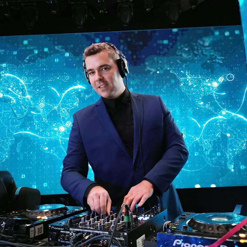 Ondra Vodný jako DJ na firemní akci, v obleku za pultem